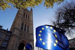 In this Jan. 22, 2019, file photo, the sun shines through European Union flags tied to railings outside parliament in London. The prospect of restoring a hard border between Ireland and Northern Ireland once Britain leaves the EU has raised fears or a return to the old reality where British army checkpoints, shootings, bombings and gun-smuggling were the norm.