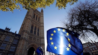 In this Jan. 22, 2019, file photo, the sun shines through European Union flags tied to railings outside parliament in London. The prospect of restoring a hard border between Ireland and Northern Ireland once Britain leaves the EU has raised fears or a return to the old reality where British army checkpoints, shootings, bombings and gun-smuggling were the norm.