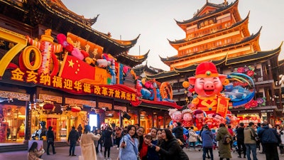 In this Jan. 17, 2019, photo, women take a selfie as others tour at the Yu Garden decorated with pig statues for Lunar New Year in Shanghai. China’s 2018 economic growth fell to a three-decade low as activity cooled amid a tariff war with Washington.