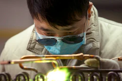 In this Friday, Feb. 24, 2017, file photo, a factory worker uses a gas torch on an air conditioning condenser unit in a factory in Jiaozhou, eastern China's Shandong Province. An official survey shows China’s manufacturing activity contracted in December, boosting pressure on Beijing to reverse an economic downturn amid trade tension with Washington.