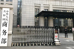 A man checks on his mobile phone near the main entrance gate of the Ministry of Commerce in Beijing, Wednesday, Jan. 9, 2019. U.S. and Chinese envoys extended trade talks into a third day Wednesday after President Donald Trump said negotiations aimed at ending a tariff war were 'going very well!'