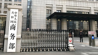 A man checks on his mobile phone near the main entrance gate of the Ministry of Commerce in Beijing, Wednesday, Jan. 9, 2019. U.S. and Chinese envoys extended trade talks into a third day Wednesday after President Donald Trump said negotiations aimed at ending a tariff war were 'going very well!'