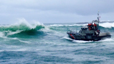 In this photo, a U.S. Coast Guard boat crew responds to three fishermen in the water after the commercial fishing vessel Mary B II capsized while crossing Yaquina Bay Bar off the coast of Newport, Oregon.