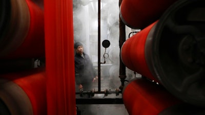In this Jan. 1, 2019, photo, a worker monitors rolls of fabric at a dyeing factory in Hangzhou in east China's Zhejiang province. China's slowing economy is squeezing the urban workers and entrepreneurs the ruling Communist Party is counting on to help transform this country from a low-wage factory floor into a prosperous consumer market.