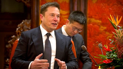 In this Jan. 9, 2019, file photo, Tesla CEO Elon Musk speaks during a meeting with Chinese Premier Li Keqiang at the Zhongnanhai leadership compound in Beijing. Electric car and solar panel maker Tesla said Friday, Jan. 18, 2019 it plans to cut its staff by about 7 percent.