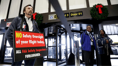 Federal Aviation Administration employee Michael Jessie, who is currently working without pay as an aviation safety inspector for New York international field office overseeing foreign air carriers, holds a sign while attending a news conference at Newark Liberty International Airport in Newark, N.J.