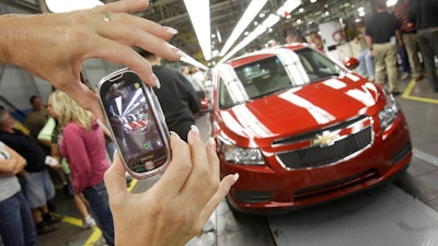 In this Sept. 8, 2010 file photo, auto worker Brenda Hedland takes a picture of the first Chevrolet Cruze compact sedan to come off the assembly line at a ceremony inside the GM factory in Lordstown, Ohio. Sales of new vehicles in the U.S. rose slightly in 2018, defying predictions and highlighting a strong economy.