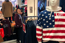 A woman tries out a sweater at a U.S. retailer GAP's flagship store in Beijing, Thursday, Jan. 10, 2019. Uncertainty over the outcome of China-U.S. trade talks is casting a pall over Asian markets as both sides kept quiet about what lies ahead.