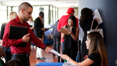 In this Jan. 30, 2018, file photo, an employee of Aldi, right, takes an application from a job applicant at a JobNewsUSA job fair in Miami Lakes, Fla. On Thursday, Jan. 3, 2019, payroll processor ADP reports how many jobs private employers added in December.