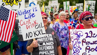 In this Aug. 6, 2017 file photo, demonstrators against the Keystone XL pipeline listen to speakers in Lincoln, Neb. Justice Department attorneys and the Canadian company behind the proposed Keystone XL oil pipeline say the U.S. government shutdown shouldn't delay a court hearing on a judge's decision to halt construction. Justice Department attorney Bridget McNeil said in a court filing Monday, Jan. 7, 20189, that federal attorneys' participation in the hearing next Monday in U.S. District Court in Great Falls isn't necessary.