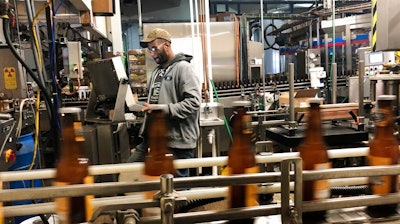 In this Jan. 14, 2019, photo, Trevor Stevens works in the bottling room at Lakefront Brewery in Milwaukee. The federal shutdown is impacting the federal agency Alcohol and Tobacco Tax and Trade Bureau, which approves licenses for new breweries, some ingredients and labels for beers sent out of state. The brewery is now waiting for the federal agency to approve the 'My Turn: Chuck' beer label, so they can sell it out of state.