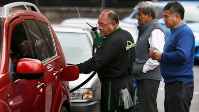 Commuters in Mexico City line up to fill their fuel tanks at a gas station, some of which are limiting how much each client can purchase.
