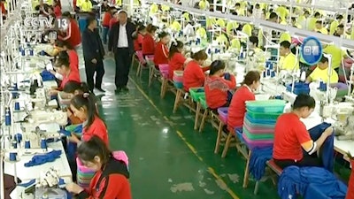 In this file image from undated video footage run by China's CCTV via AP Video, Muslim trainees work in a garment factory at the Hotan Vocational Education and Training Center in Hotan, Xinjiang, northwest China. A U.S. company that stocks college bookstores with t-shirts and other team apparel cut ties Wednesday, Jan. 9, 2019, with a Chinese company that drew workers from an internment camp holding targeted members of ethnic minority groups.