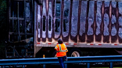 In this Thursday, Jan. 3, 2019, file photo, a worker looks at a charred semitrailer after a wreck with multiple fatalities on Interstate 75, south of Alachua, near Gainesville, Fla. The 35-day partial government shutdown stopped the National Transportation Safety Board from dispatching investigators to 22 accidents that killed 30 people, jeopardizing some perishable evidence, the agency said Monday, Jan. 28, 2019.
