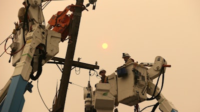 In this November 9, 2018 file photo, Pacific Gas & Electric crews work to restore power lines in Paradise, California.
