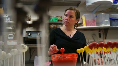 n this Friday, Jan. 11, 2019, photo Yael Krigman dips cakepops at her bakery Baked by Yael in Washington. The bakery is located across from Smithsonian's National Zoo that is closed because of the partial government shutdown.