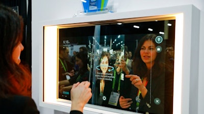 A woman demonstrates the Artemis smart mirror at the CareOS booth during CES Unveiled at CES International, Sunday, Jan. 6, 2019, in Las Vegas. The interactive mirror has video capture, virtual try-ons, facial and object recognition, and can give the user video instruction on specific makeup products, among other things.