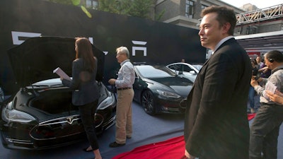 In this April 22, 2014, file photo. Tesla Motors CEO Elon Musk, right, looks on as a set of Tesla Model S sedans are delivered to its first customers in China at an event in Beijing. Musk said Monday, Jan. 7, 2019 on twitter that the automaker is breaking ground for a Shanghai factory and will start production of its Model 3 by the end of the year.