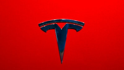 This Aug. 8, 2018, file photo shows a Tesla emblem on the back end of a Model S in the Tesla showroom in Santa Monica, Calif. The parents of a Florida teenager killed when a Telsa sedan crashed and caught fire last year are suing the electric car company alleging that the battery pack on its electric Model S is defective and can erupt into intense fires.