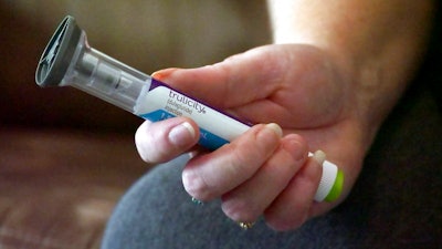 In this July 11, 2018, file photo, Bridgett Snelten holds her Trulicity injection at her home in Sandy, Utah. Drugmaker Eli Lilly has started posting price information online for drugs advertised on TV. On Tuesday, Jan. 8, 2019, the company began running TV ads for Trulicity, a popular diabetes drug, that don’t give the price but direct viewers to the website.