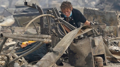 In this Oct. 9, 2017 file photo, Kristine Pond reacts as she searches the remains of her family's home destroyed by a fire in Santa Rosa, Calif. Investigators say a deadly 2017 wildfire that killed 22 people in California's wine country was caused by a private electrical system, not embattled Pacific Gas & Electric Co. The state's firefighting agency said Thursday, Jan. 24, 2019, that the Tubbs Fire started next to a residence. They did not find any violations of state law.