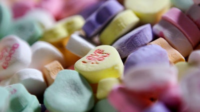 In this Jan. 14, 2009 file photo, colored 'Sweethearts' candy is held in bulk prior to packaging at the New England Confectionery Company in Revere, Mass. The candies won't be on store shelves this Valentine's Day. The New England Confectionary Co., or Necco, had been making the popular candies since 1886. But the company filed for bankruptcy protection last spring. Ohio-based Spangler Candy Co. bought Necco in May. But Spangler said Thursday, Jan. 24, 2019, that it didn't have time to bring Sweethearts to market this Valentine's season.