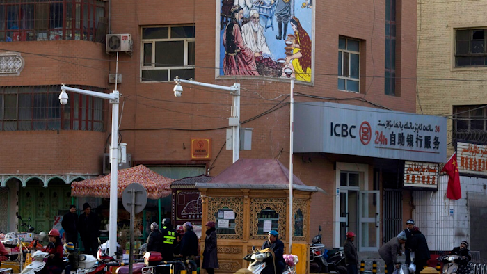 In this Nov. 5, 2017, file photo, residents pass by a security checkpoint and surveillance cameras mounted on a street in Kashgar in western China's Xinjiang region. The Chinese database Victor Gevers found online was not just a collection of old personal details. The discovery by Gevers, a Dutch cybersecurity researcher who revealed it on Twitter last week, has given a rare glimpse into China’s extensive surveillance of Xinjiang, a remote region home to an ethnic minority population that is largely Muslim. The area has been blanketed with police checkpoints and security cameras that apparently are doing more than just recording what happens. The database Gevers found appears to have been recording people’s movements tracked by facial recognition technology, he said, logging more than 6.7 million coordinates in a span of 24 hours.