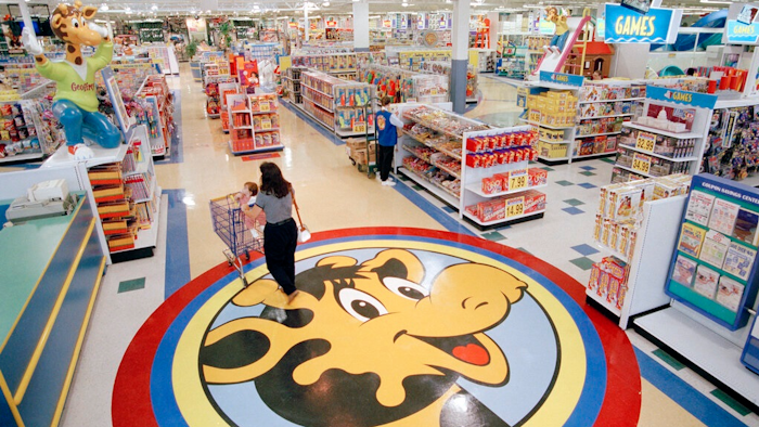 In this July 30, 1996, file photo, a woman pushes a shopping cart over a graphic of Toys R Us mascot Geoffrey the giraffe at the Toys R Us store in Raritan, N.J. Richard Barry, a former Toys R Us executive and now CEO of the new company called Tru Kids Inc., is exploring freestanding stores, shops within existing stores as well as e-commerce. Tru Kids, owned by former investors of Toys R Us, will manage the Toys R Us, Babies R Us and Geoffrey brands.s.