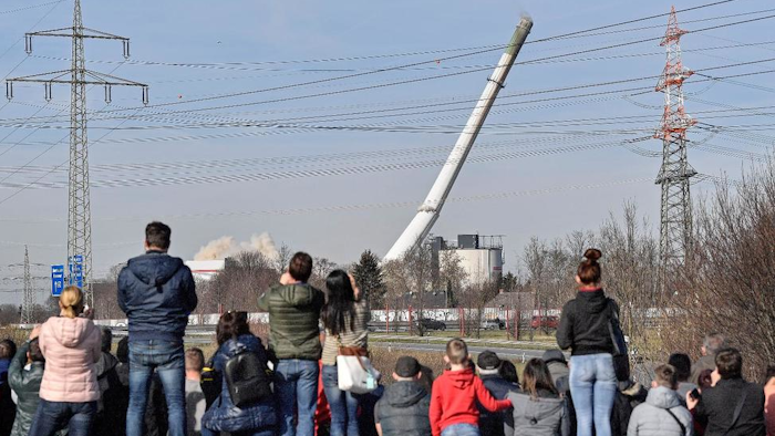 People watching the fall of a chimney during the blasting of a former coal-fired power station in Dortmund, Germany, Sunday, Feb. 17, 2019.