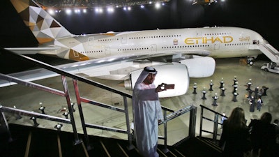 In this Dec. 18, 2014, file photo, an Emirati man takes a selfie in front of a new Etihad Airways A380 in Abu Dhabi, United Arab Emirates. Abu Dhabi-based Etihad Airways said Thursday, Feb. 14, 2019, that it has restructured planned airplane purchases from Airbus and Boeing as the government-owned carrier faces financial turbulence.