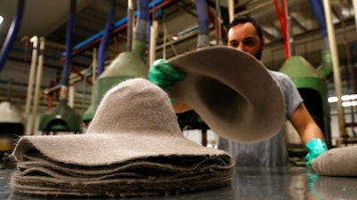 A man piles felt hats inside Borsalino's hat factory, in Spinetta Marengo, near Alessandria, Italy, Thursday, Jan. 17, 2019. Borsalino's prized felt hats are handmade by 80 workers in its Piemonte factory, many who have worked there for decades, with original machinery that use hot water and steam to transform rabbit fur into highly prized felt, that is formed into clochards, dyed and molded by hand to create the latest styles.