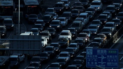 In this Dec. 11, 2018, file photo, a beam of sunlight is cast on vehicles on a city ring-road clogged with heavy traffic during the morning rush hour in Beijing. China’s auto sales fell for an eighth month in January, 2019, extending a painful decline for the biggest global market.