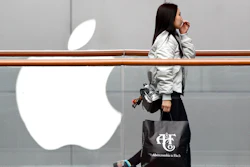 A woman carries a paper bag containing goods purchased from American brand Abercrombie & Fitch walks past an Apple store at the capital city's popular shopping mall in Beijing, Tuesday, Feb. 26, 2019. American companies in China increasingly worry U.S.-Chinese relations will deteriorate and are 'hedging their bets' by delaying investment or moving operations, a business group reported Tuesday.