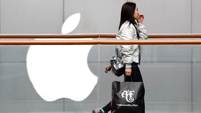 A woman carries a paper bag containing goods purchased from American brand Abercrombie & Fitch walks past an Apple store at the capital city's popular shopping mall in Beijing, Tuesday, Feb. 26, 2019. American companies in China increasingly worry U.S.-Chinese relations will deteriorate and are 'hedging their bets' by delaying investment or moving operations, a business group reported Tuesday.