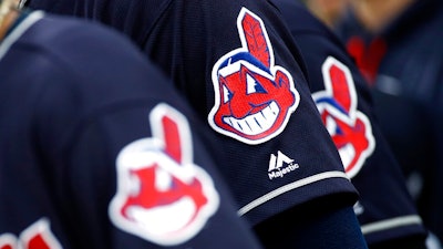 In this June 19, 2017 file photo, members of the Cleveland Indians wear uniforms featuring mascot Chief Wahoo as they stand on the field for the national anthem before a baseball game against the Baltimore Orioles in Baltimore. The maker of Cleveland's ballpark mustard is removing the Chief Wahoo logo from its branding and packaging to maintain longstanding ties with the Cleveland Indians baseball team. The Indians have told official partners like Bertman Foods Co., the maker of Bertman Original Ballpark Mustard, those relationships can't continue unless they stop using Chief Wahoo.
