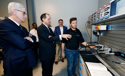 U.S. Secretary of Labor Alexander Acosta, center, asks about the hydraulic maintenance and troubling shooting simulator with a student, while Mississippi Gov. Phil Bryant, left, listens, at the Continental Tire manufacturing plant, Friday, Feb. 8, 2019, in Clinton, Miss., during a tour of the Continental Tire Training Center.