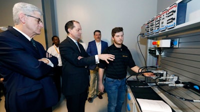 U.S. Secretary of Labor Alexander Acosta, center, asks about the hydraulic maintenance and troubling shooting simulator with a student, while Mississippi Gov. Phil Bryant, left, listens, at the Continental Tire manufacturing plant, Friday, Feb. 8, 2019, in Clinton, Miss., during a tour of the Continental Tire Training Center.