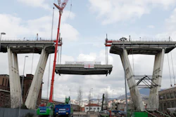 Cranes lower a section of the Morandi bridge in Genoa, Italy, Saturday, Feb. 9, 2019. Workers taking apart the remains of a bridge which collapsed in Aug. 2018 are set to remove a 40 meter beam, seen in between the red machinery. A large section of the bridge collapsed over an industrial area in the Italian city of Genova last summer during a sudden and violent storm, leaving vehicles crushed in rubble below and killing 43 people.