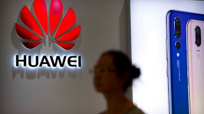 In this July 4, 2018, file photo, a shopper walks past a Huawei store at a shopping mall in Beijing. Canada’s national game _ brought to you by China’s Huawei. As a feud deepens between Beijing and Ottawa over the telecom giant, the company’s sponsorship of the flagship “Hockey Night in Canada” broadcast raised questions about its involvement in a beloved national institution.