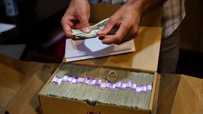 In this June 27, 2017 file photo, the proprietor of a medical marijuana dispensary prepares his monthly tax payment, over $40,000 in cash, at his Los Angeles store. Congress on Wednesday, Feb. 13, 2019, was urged to fully open the doors of the nation's banking system to the legal marijuana industry, a change that supporters say would reduce the risk of crime and resolve a litany of problems for pot companies from paying taxes to getting a loan.