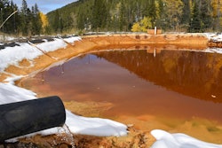 In this Oct. 12, 2018 photo, water contaminated with arsenic, lead and zinc flows from a pipe out of the Lee Mountain mine and into a holding pond near Rimini, Mont. The community is part of the Upper Tenmile Creek Superfund site, where dozens of abandoned mines have left water supplies polluted and residents must use bottled water.