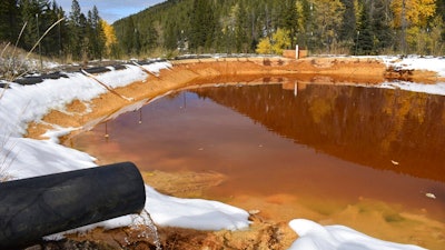 In this Oct. 12, 2018 photo, water contaminated with arsenic, lead and zinc flows from a pipe out of the Lee Mountain mine and into a holding pond near Rimini, Mont. The community is part of the Upper Tenmile Creek Superfund site, where dozens of abandoned mines have left water supplies polluted and residents must use bottled water.