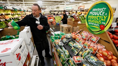 Dave Ruble stocks the imperfect produce section at the Hy-Vee grocery store in Urbandale, Iowa. After enjoying a brief spotlight in supermarket produce sections, blemished fruits and vegetables may already be getting tossed back in the trash.