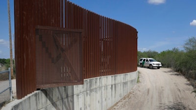 In this Aug. 11, 2017, file photo, a U.S. Customs and Border Patrol vehicle passes along a section of border levee wall in Hidalgo, Texas. The U.S. government is preparing to begin construction of more border walls and fencing in South Texas' Rio Grande Valley, likely on federally-owned land set aside as wildlife refuge property. Heavy construction equipment is supposed to arrive starting Monday. A photo posted by the nonprofit National Butterfly Center shows an excavator parked on its property.