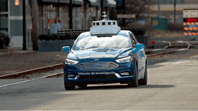 In this Dec. 18, 2018, photo one of the test vehicles from Argo AI, Ford's autonomous vehicle unit, navigates through the strip district near the company offices in Pittsburgh. Even the most optimistic experts say it will be 10 years before self-driving vehicles are everywhere, but others believe it will take decades. The biggest reasons are camera and laser sensors that can’t see through heavy snow or figure out where to go if lane lines are covered.