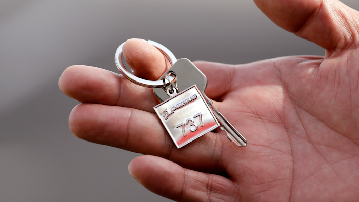 In this March 21, 2018, file photo a Thai Lion Air employee displays a ceremonial key to the company's newest plane, Boeing's first 737 MAX 9 jet, following a delivery ceremony to the airline in Seattle. The United States and many other countries have grounded the Max 8s and larger Max 9s as Boeing faces the challenge of proving the jets are safe to fly amid suspicions that faulty sensors and software contributed to the two crashes in less than five months.
