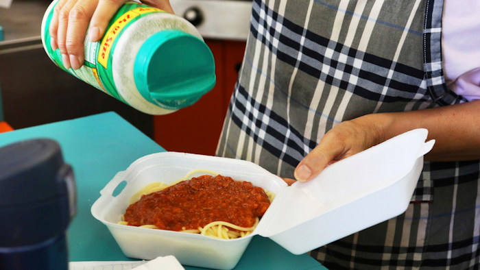 In this Thursday, March 14, 2019 photo, Belinda Lau, manager of the Wiki Wiki Drive Inn takeout restaurant in Honolulu, sprinkles cheese on an order of spaghetti in a styrofoam container. Hawaii would be the first state in the U.S. to ban most plastics used at restaurants under legislation that aims to cut down on waste that pollutes the ocean. Dozens of cities across the country have banned plastic foam containers, but Hawaii would be the first to bar them statewide.