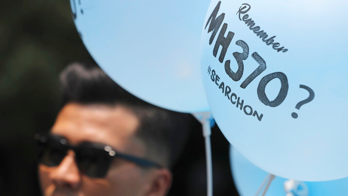 A volunteer gives out balloons printed with MH370 during a Day of Remembrance for MH370 event in Kuala Lumpur, Malaysia, Sunday, March 3, 2019. Five years ago, Malaysia Airlines Flight MH370, a Boeing 777, had gone missing the day before while over the South China Sea with 239 people on board.
