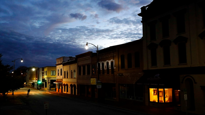 In this Oct. 28, 2017, file photo the storefront window of a portrait studio is lit up along a downtown street at dusk in Lumberton, N.C. Although small businesses vary widely in terms of size, industry and issues, they do appear to be generally united by a growing uneasiness about the economy. Several surveys and economic reports released in recent weeks show that company owners have more trust in their businesses than the national or local economy, and that they’re running their businesses more conservatively in response to uncertainty about overall business conditions.