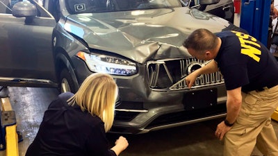 In this March 20, 2018, file photo provided by the National Transportation Safety Board, investigators examine a driverless Uber SUV that fatally struck a woman in Tempe, Ariz. A prosecutor has determined that Uber is not criminally liable in the crash that killed 49-year-old Elaine Herzberg.